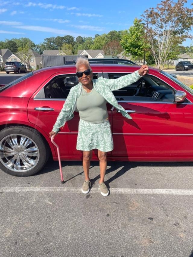 Mimi posing joyfully with red car